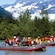 Inflatable rafts filled with people in life jackets float just off the coastline lined with trees